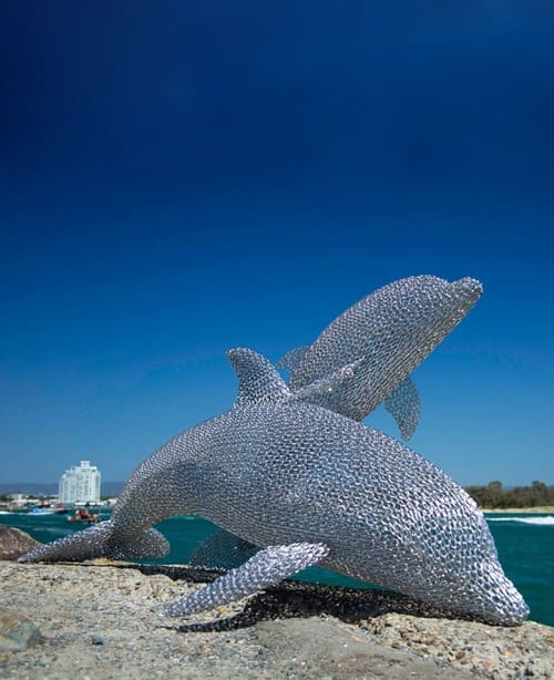 Harmony -Mike-Van-Dam -Dolphin-stainless-steel-sculpture on the rocks